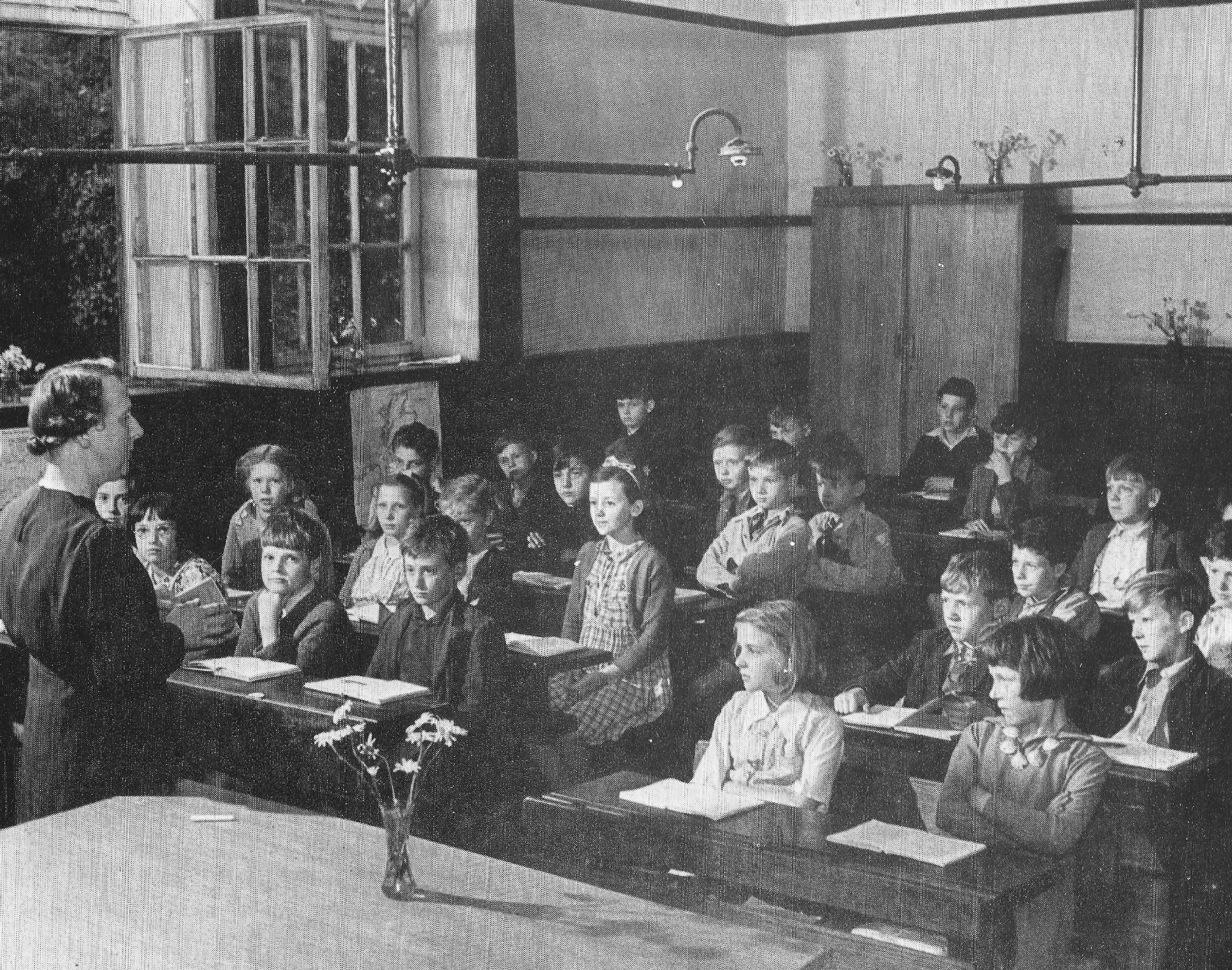The National School in Lobards Wynd, with flowers on the teachers desk and the overhead gas pipes