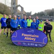Bronwyn Mayo at Fountains Abbey having completed her 250th park run, with her group of supporters
