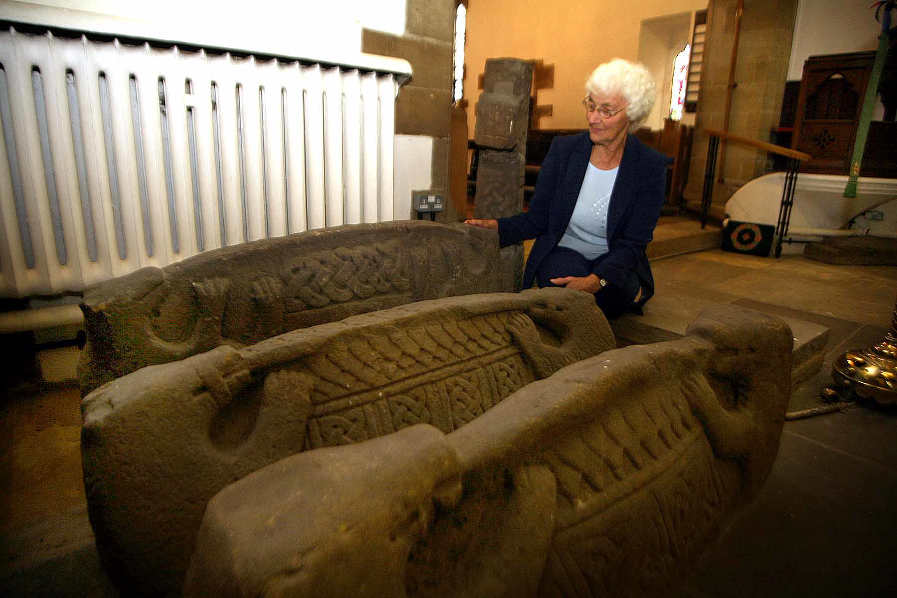 Doreen Newcombe with the hogback stones at St Thomas Church, Brompton, in 2006