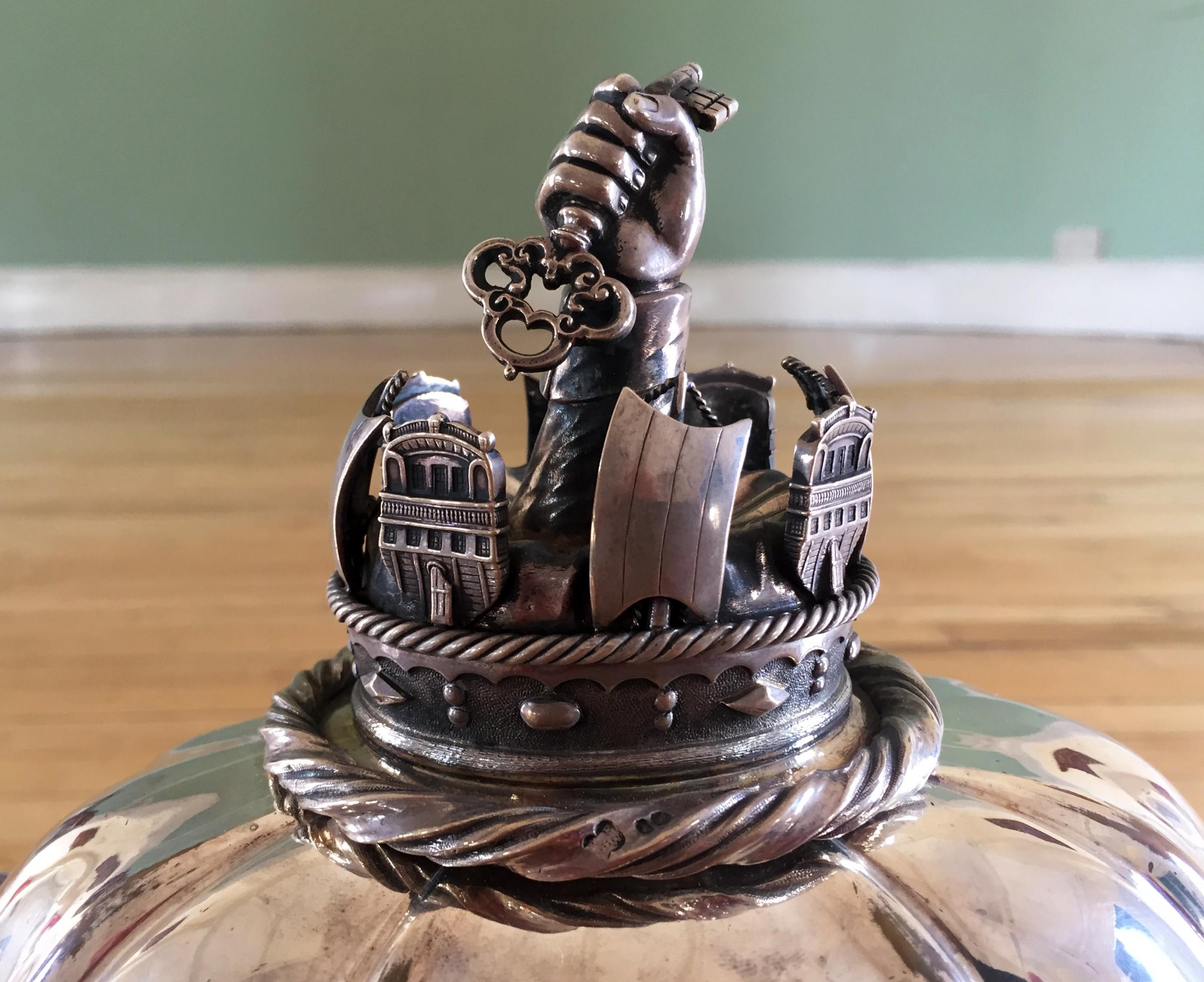 A hand holding a gilded key - a little bent over time - on top of the tureen. It symbolises how Capt Boss opened up Northallerton to democracy