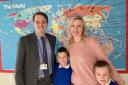 Headteacher Mark Dipple with Ukrainian mum, Maria Vasylyshyn, and her sons, Ostap and Artem, in front of the map showing the pupils' countries