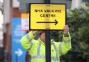 A worker hangs a direction sign to an NHS Covid Vaccine Centre