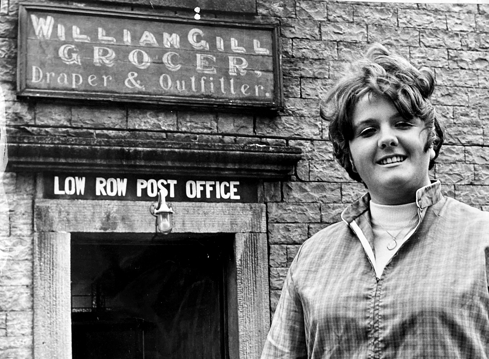 Mini-skirted Anne Gill outside Low Row Post Office in 1970 when, aged 19, she had become the youngest subpostmaster in the country. Her grandfather, William Gill, whose name can still be seen over the door advertising the non postal items that he