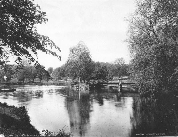 Darlington and Stockton Times: A footbridge in South Park. The Skerne used to fill this boating lake beneath the Park Lodge. We're looking south, towards the Parkside bridge, with Blackwell Grange in the distance out of sight behind the trees. The bridge took people from Penny