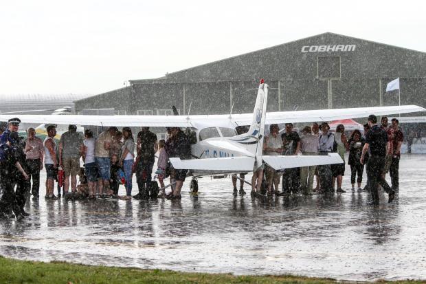 Darlington and Stockton Times: The sun doesn't always smile on the Teesside airshow as this picture of spectators huddling under the wings during a downpour shows