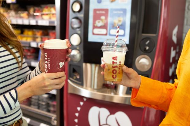 Darlington and Stockton Times: One person holding a hot drink (left) and another person holding a cold drink (right) in front of a new Costa Express machine (Costa Coffee)