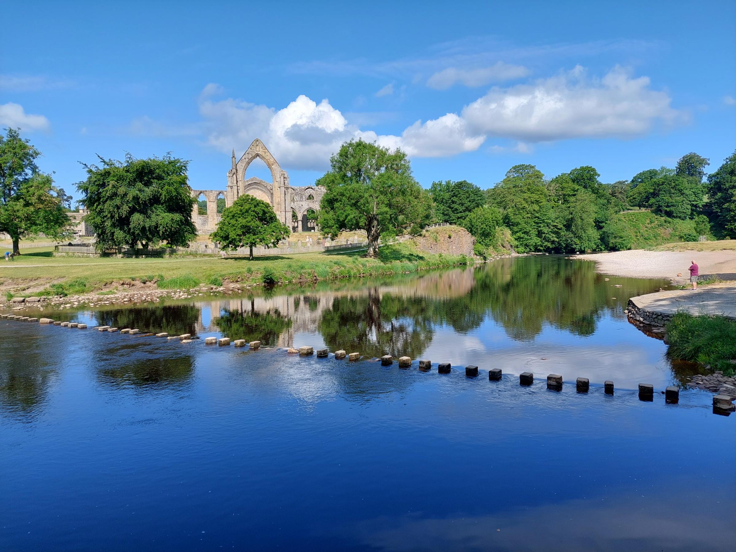 the stepping stones over the River Wharfe with Bolton Abbey Priory, by Ian Naylor 