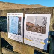 Objectors have posted signs close to the site of the proposed mast, with Whernside behind