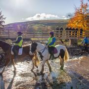 Horse riders Jane Baker and Lucy Sterry from Arkle Moor Riding Centre and cyclist Stuart Price from Dales Bike Centre, with rangers and volunteers on the footbridge, enjoy the restored crossing at Slei Gill in Arkengarthdale